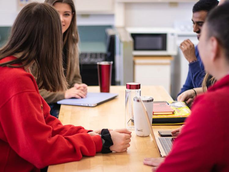 A group of students sitting and chatting in a classroom
