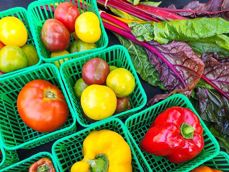 Small baskets full of vegetables, including bell peppers and tomatoes