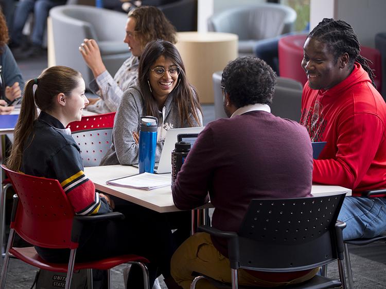 Four Students Sitting at Table and Chatting