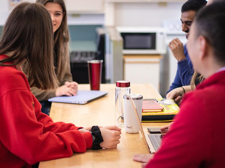 Four Students sitting at a table and chatting