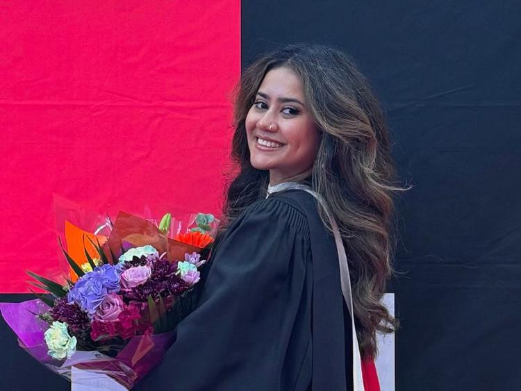 Political Science grad Anindita Ponkshe holding flowers at her graduation