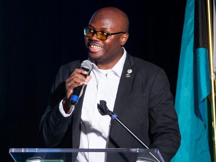 Guelph Grad Charles Hamilton holding a microphone while speaking at a podium.