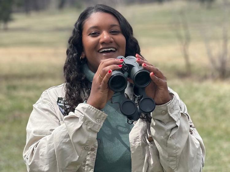 Grad Shanelle Thevarajah posing with binoculars