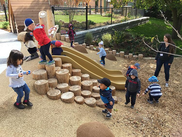 children playing at a daycare while a teacher watches them