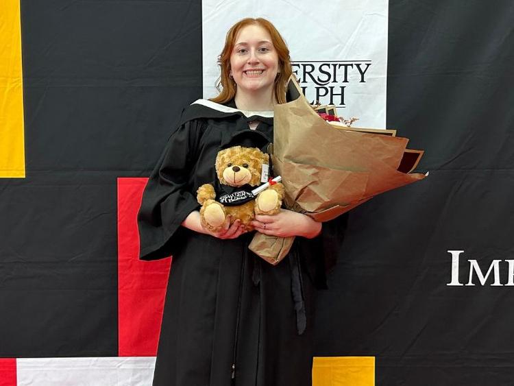 Jacquelyn Passarelli at her U of G graduation posing with flowers.