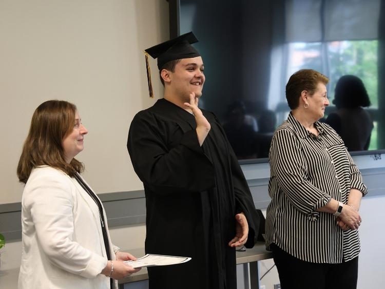 A graduating student receiving an award waves to his family in the crowd.