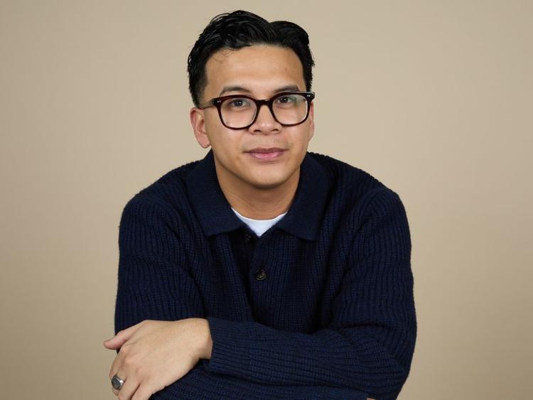 Business Grad Matthew Martin poses for a picture wearing glasses and a v neck sweater.