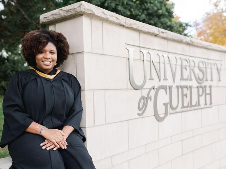 Guelph Grad Kia-Marie Parsons stands in front of the U of G sign at her convocation