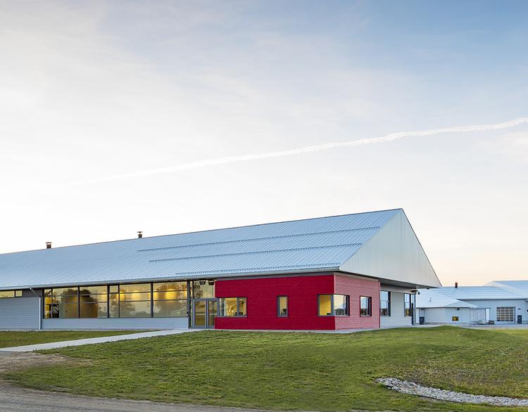 Red barn surrounded by green grass and blue sky.