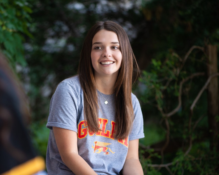 person outdoors wearing Guelph Gryphons t-shirt smiles in conversation