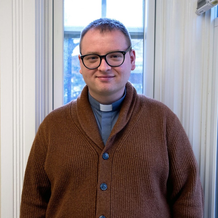 Photo of Father Patrick Ohl in sweater in front of window