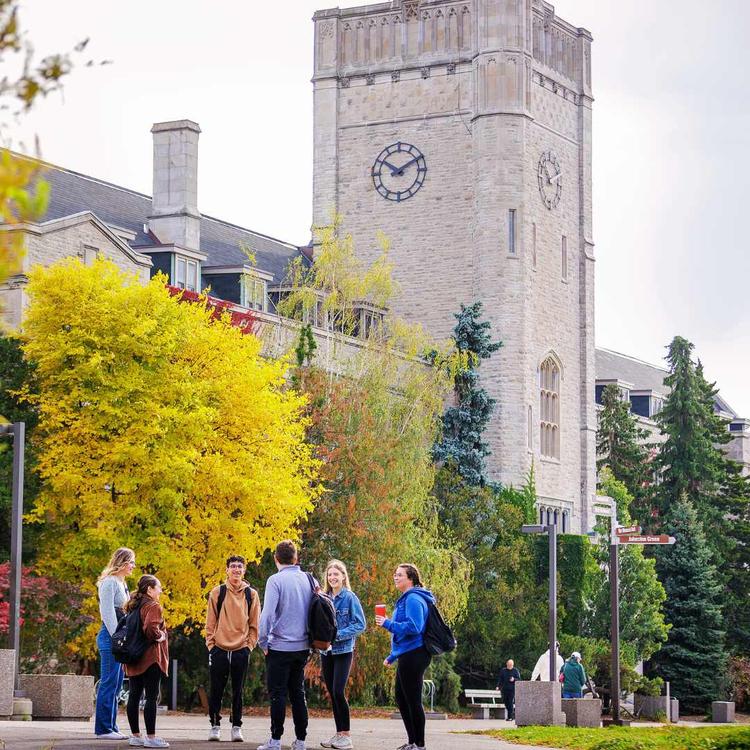A group of students standing and talking to each other. Background featuring the University of Guelph's Johnston Hall building.