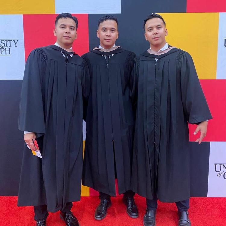 Business Grad Matthew Martin an identical triplet poses at his convocation along with his two brothers.