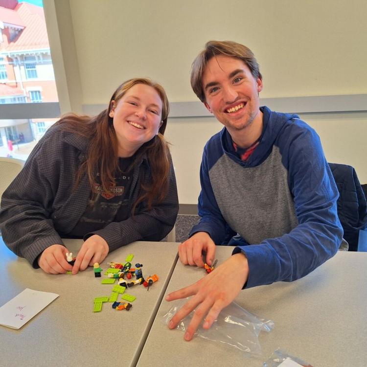 A student and a volunteer smile, working on a puzzle together.