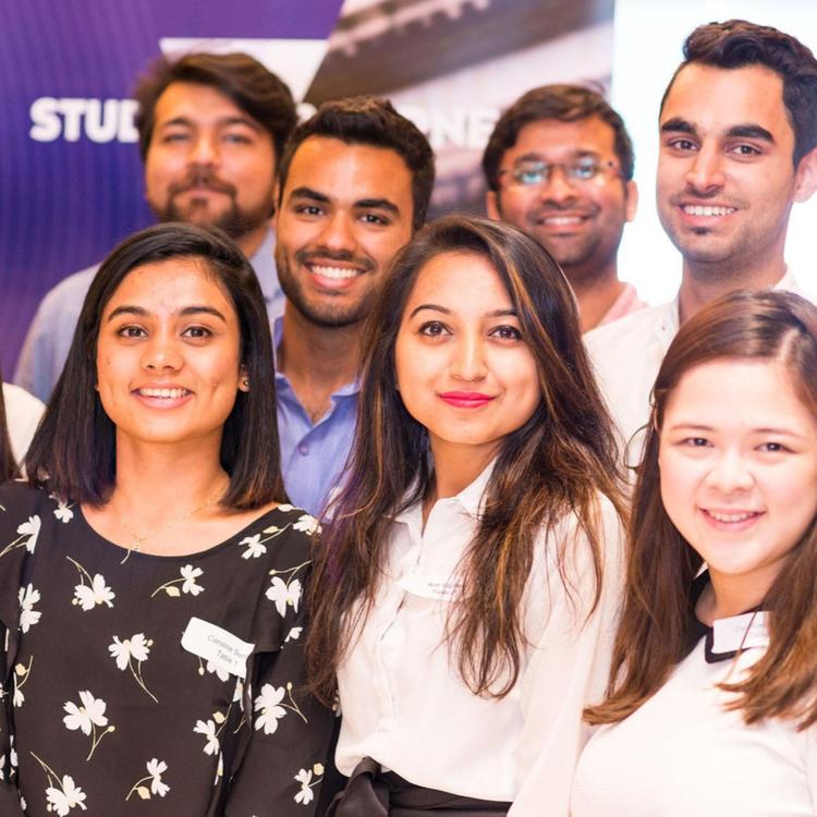A diverse group of young professionals smile at the camera.