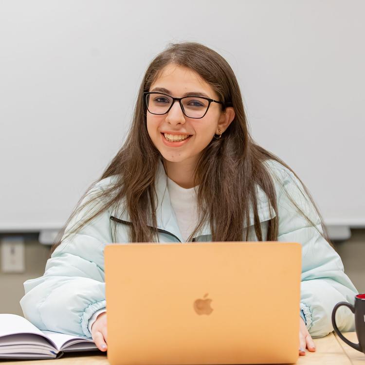 A student working on their laptop smiles.