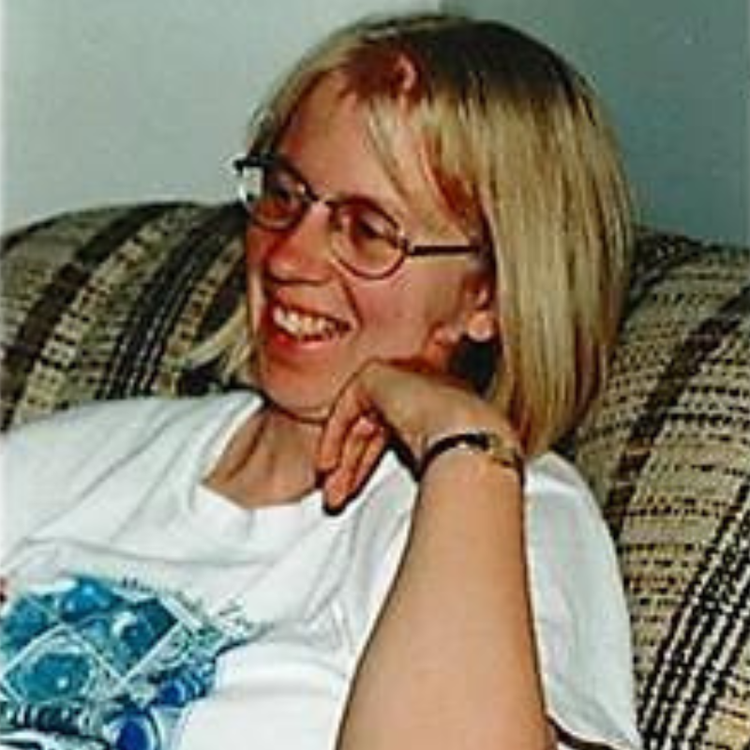 Leslie Rye sitting on a couch and smiling.