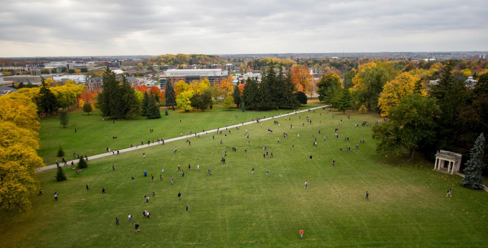 View of Johnston Green from top of Johnston Hall, various trees surrounding background as students walk across Johnston Green