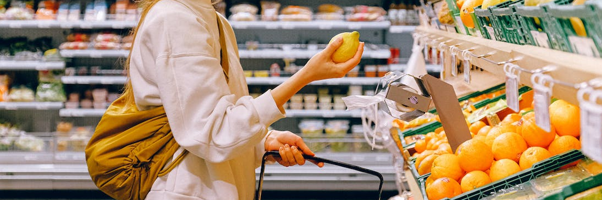 a photo of a woman picking out an orange in the grocery store