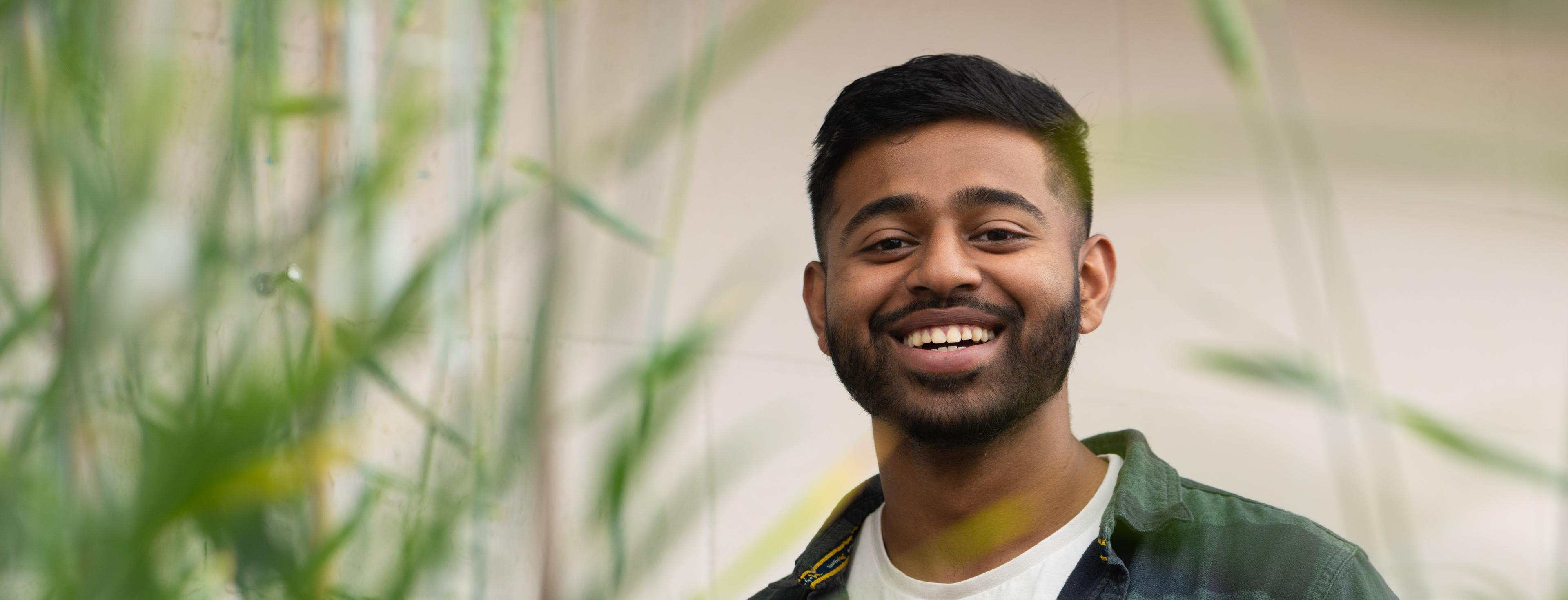 Picture of a student smiling in a field of grass. 