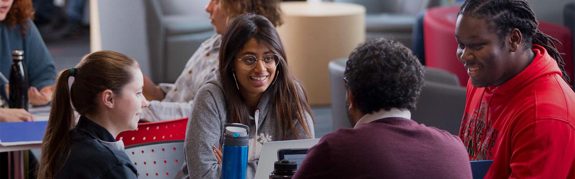 a group of diverse students sitting at a table and chatting