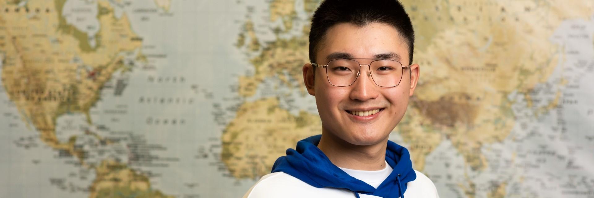 person smiling standing in front of world map