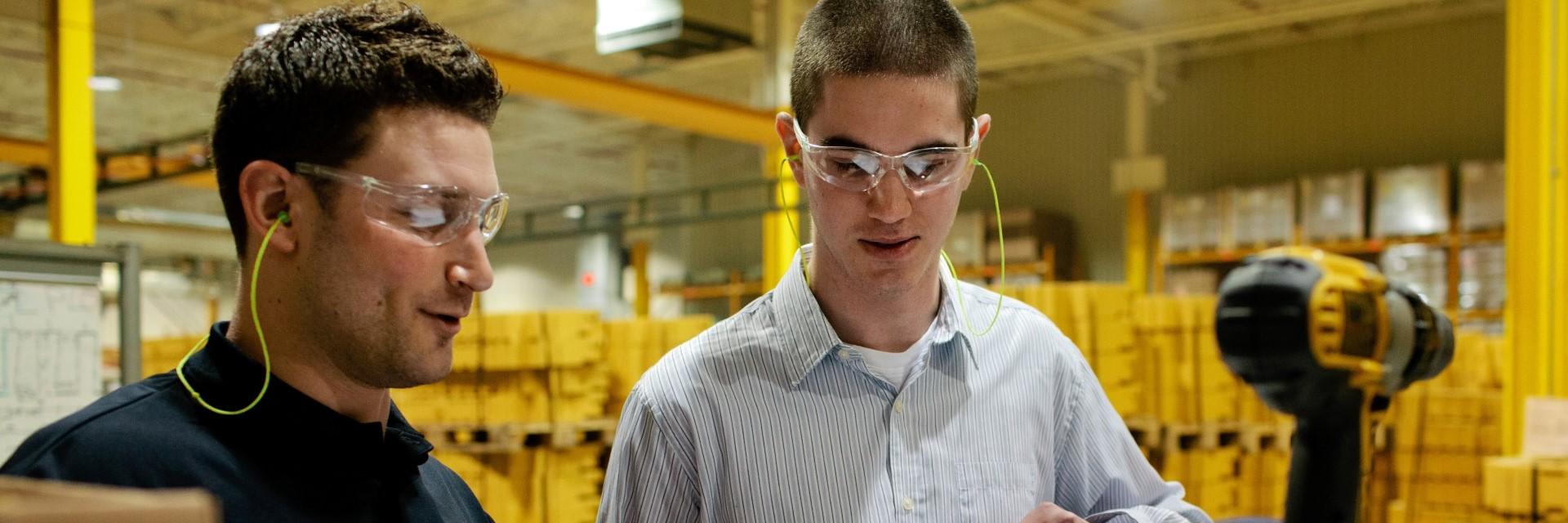 Two engineers wearing protective goggles working in a warehouse