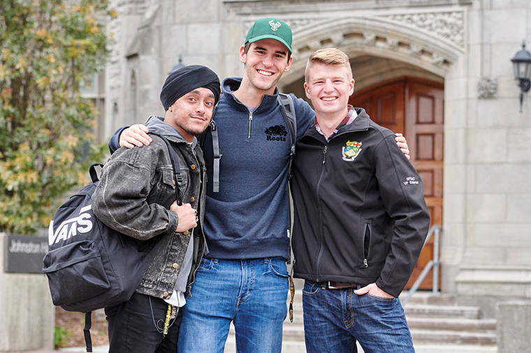 three students with their arms around each other, posing in front of War Memorial Hall