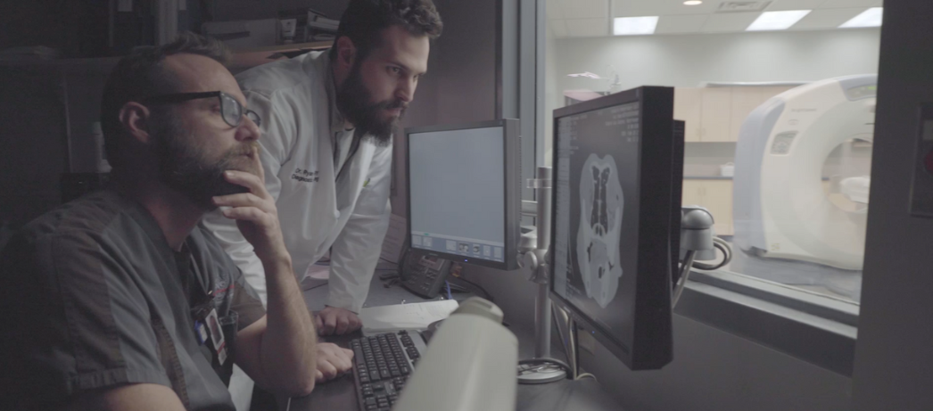 Two men looking at a computer screen displaying radiographs.