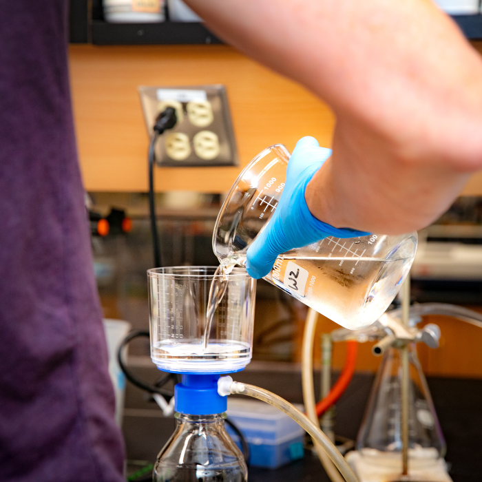 Student pours from a beaker in a lab