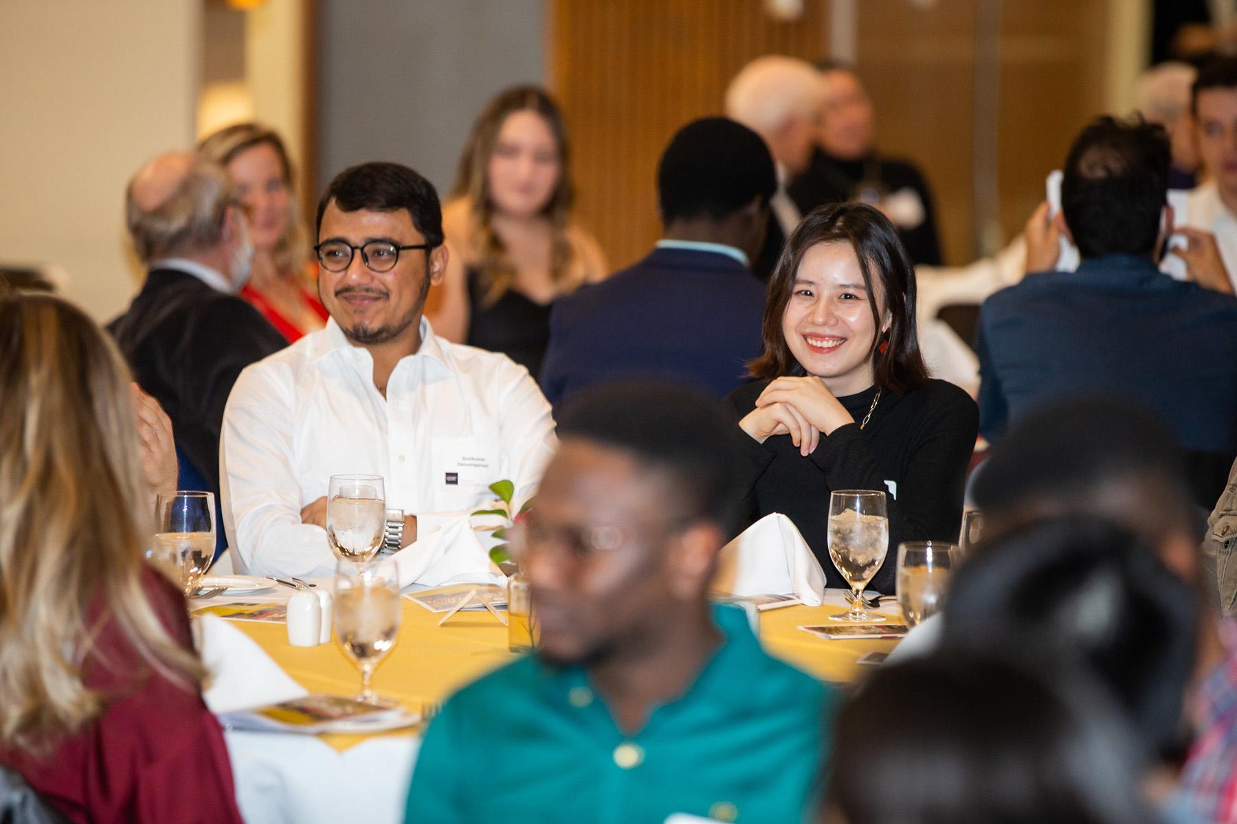 Two students sitting at a table smiling. 