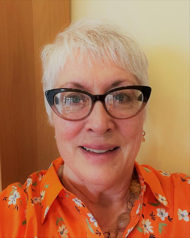 headshot of Patricia Turner wearing glasses with orange dress shirt