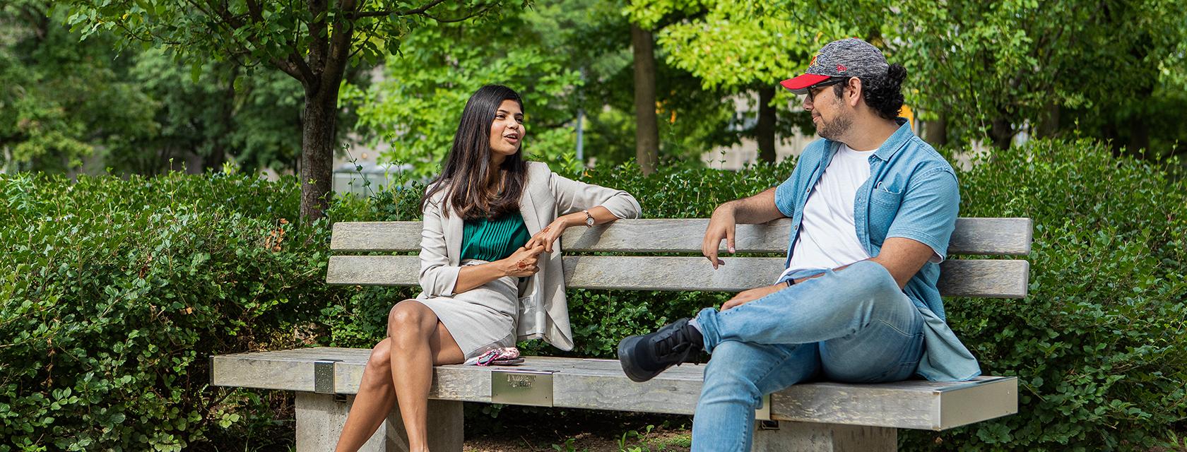 two people sitting on a bench and chatting
