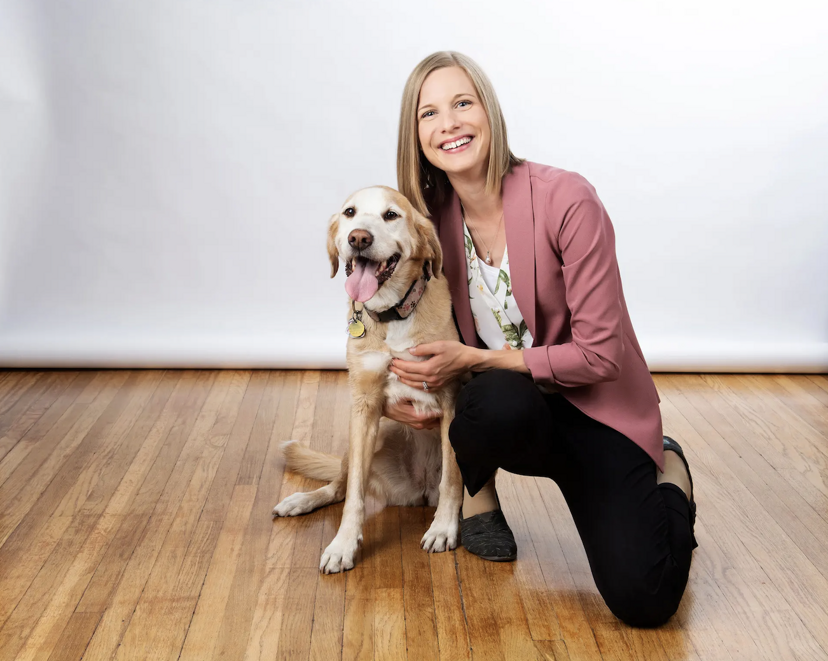 Dr. Katie Clow kneels next to a dog.