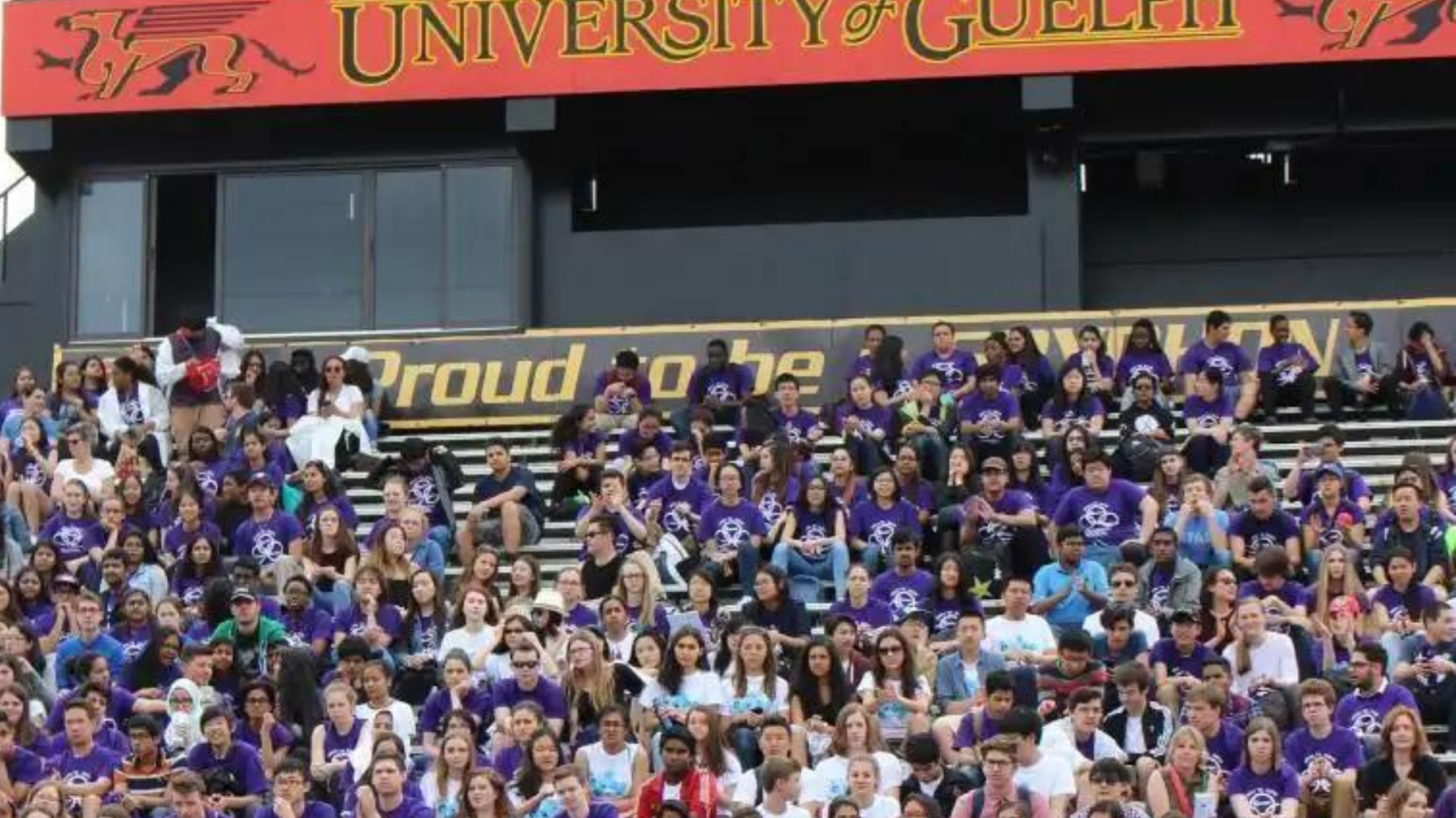 Large group of high school students in purple shirts sitting on bleachers at the University of Guelph for a Battle STEM event. 