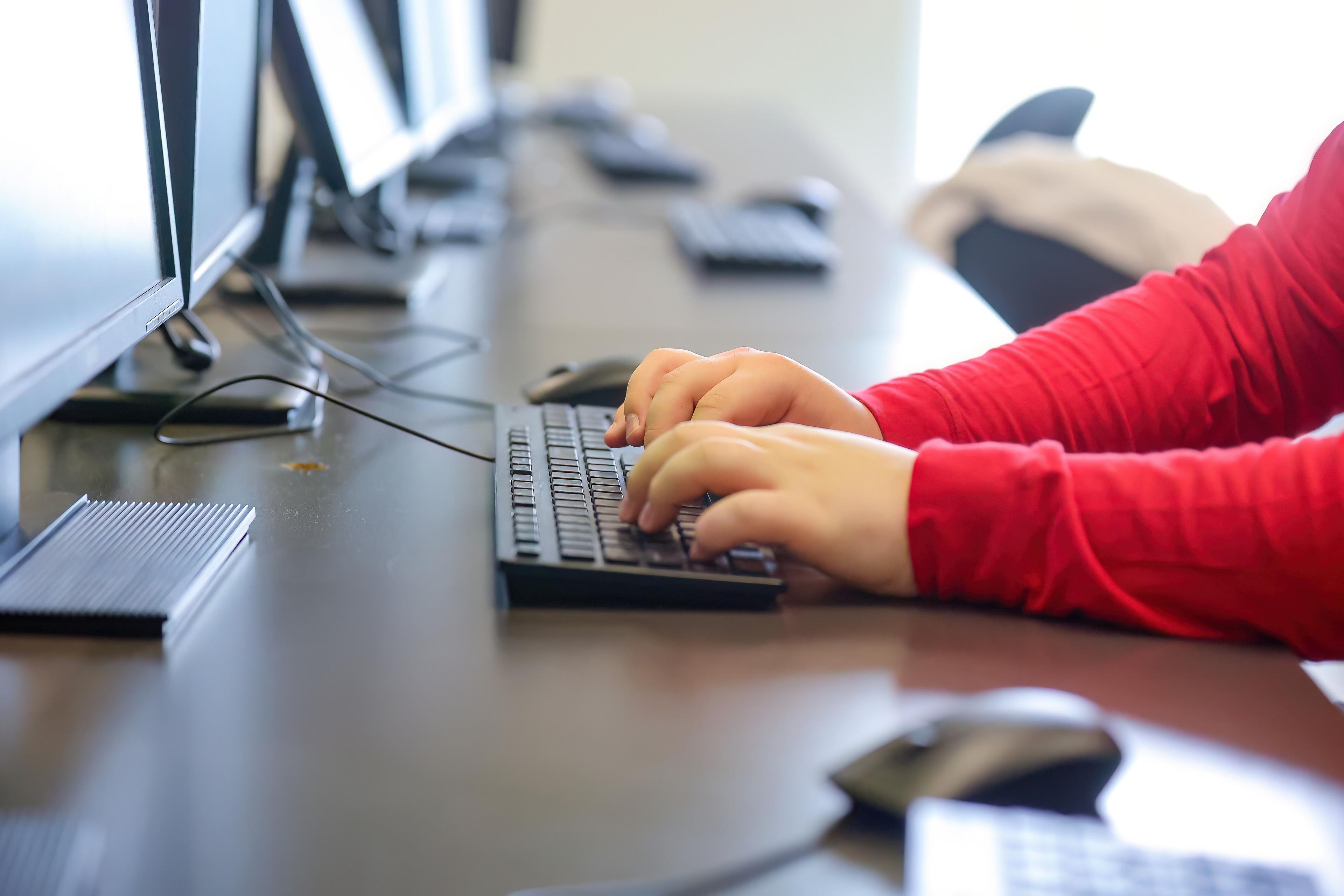 Student typing on a keyboard in a lab