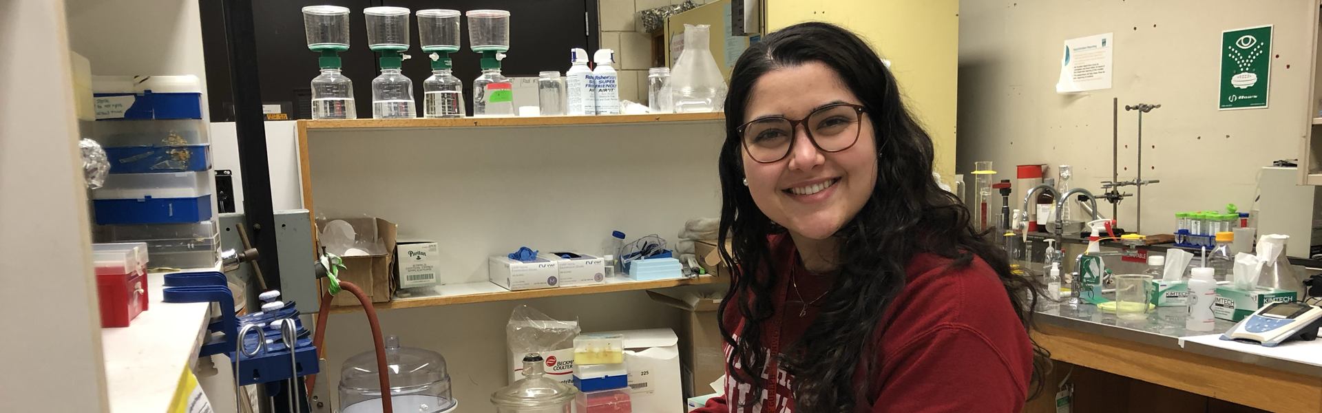 young woman smiling with lab equipment in backround
