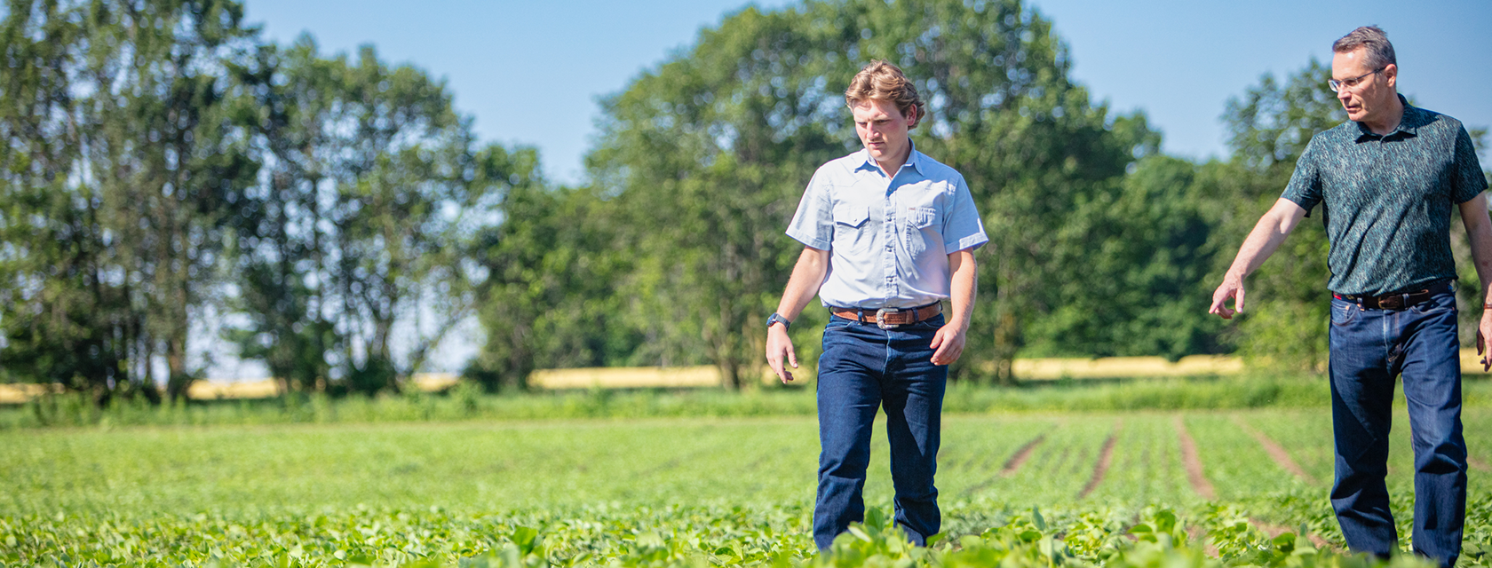 a student and a faculty member tour a crop field