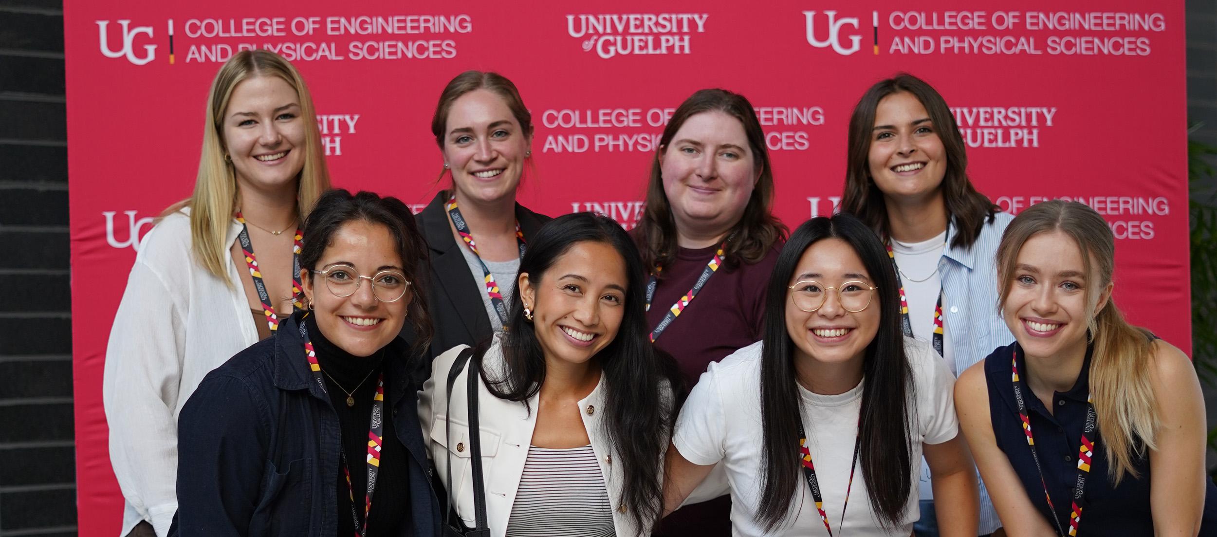 Group of participants in 2024 RISE conference stand together smiling at the camera in front of U of G background