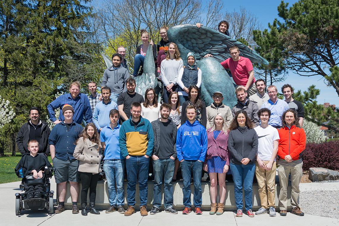 Group of students posing on and around griffin statue