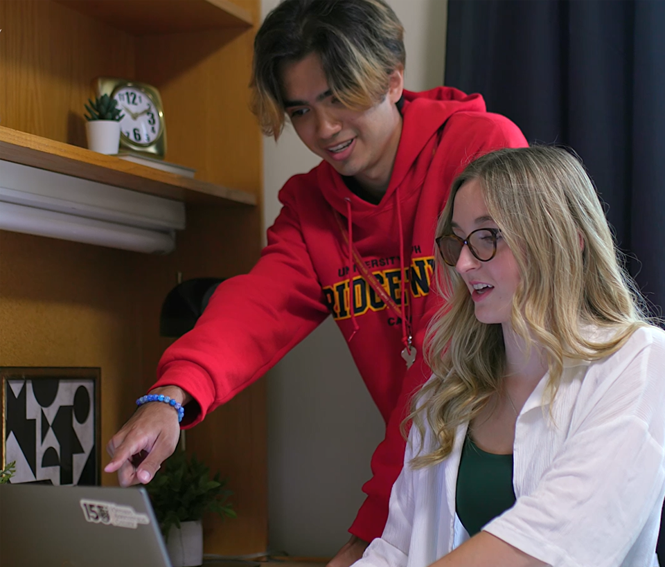 two classmates pointing to a computer screen in residence