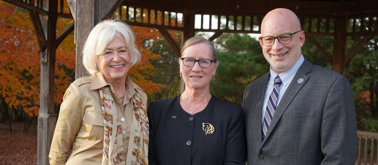 three people in formal attire standing outside