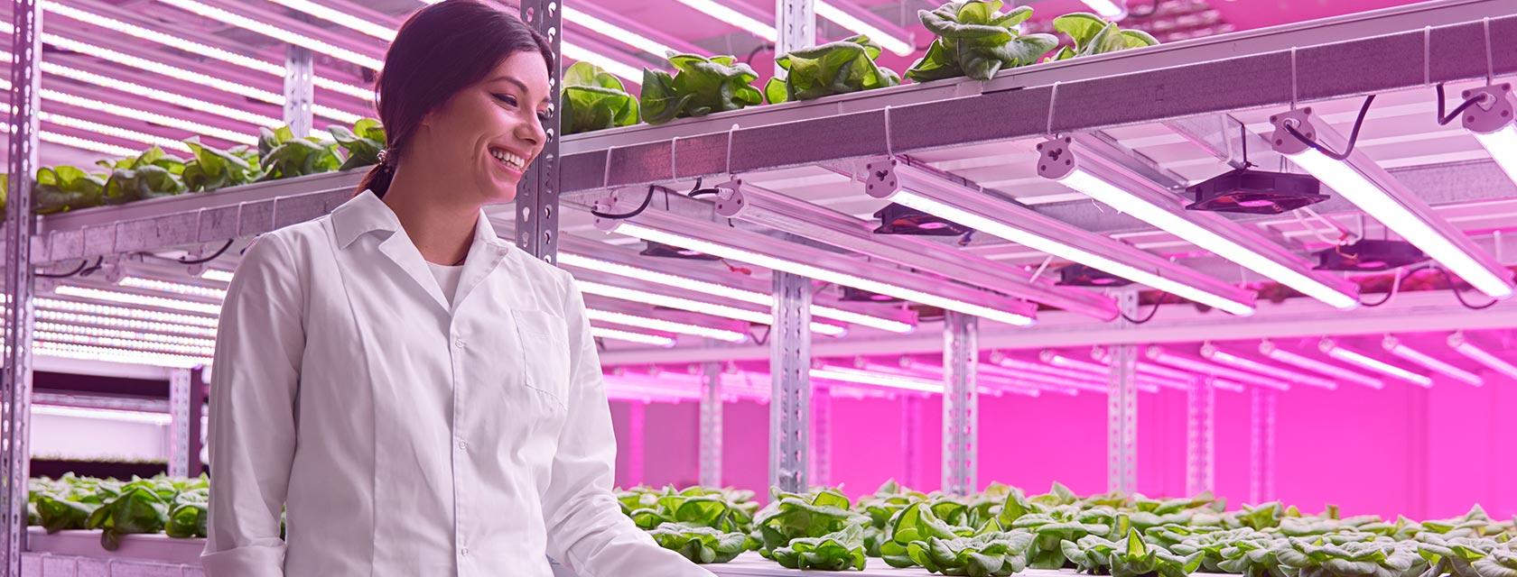 a woman in an indoor greenhouse smiling