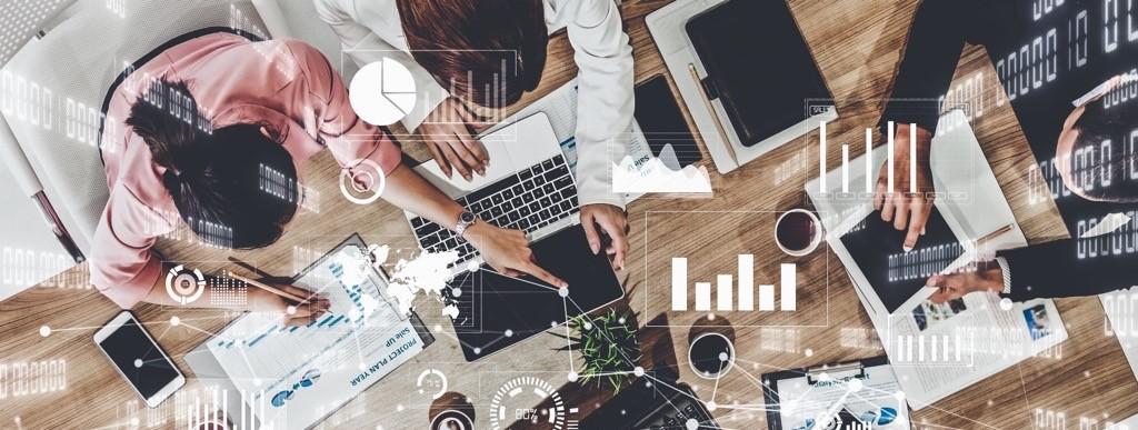 People working together at a desk with technological symbols around them