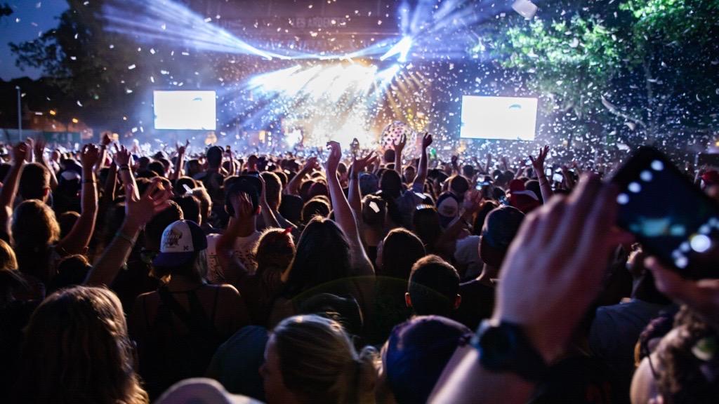 A vibrant crowd enjoying a concert, surrounded by colorful confetti cascading from above.