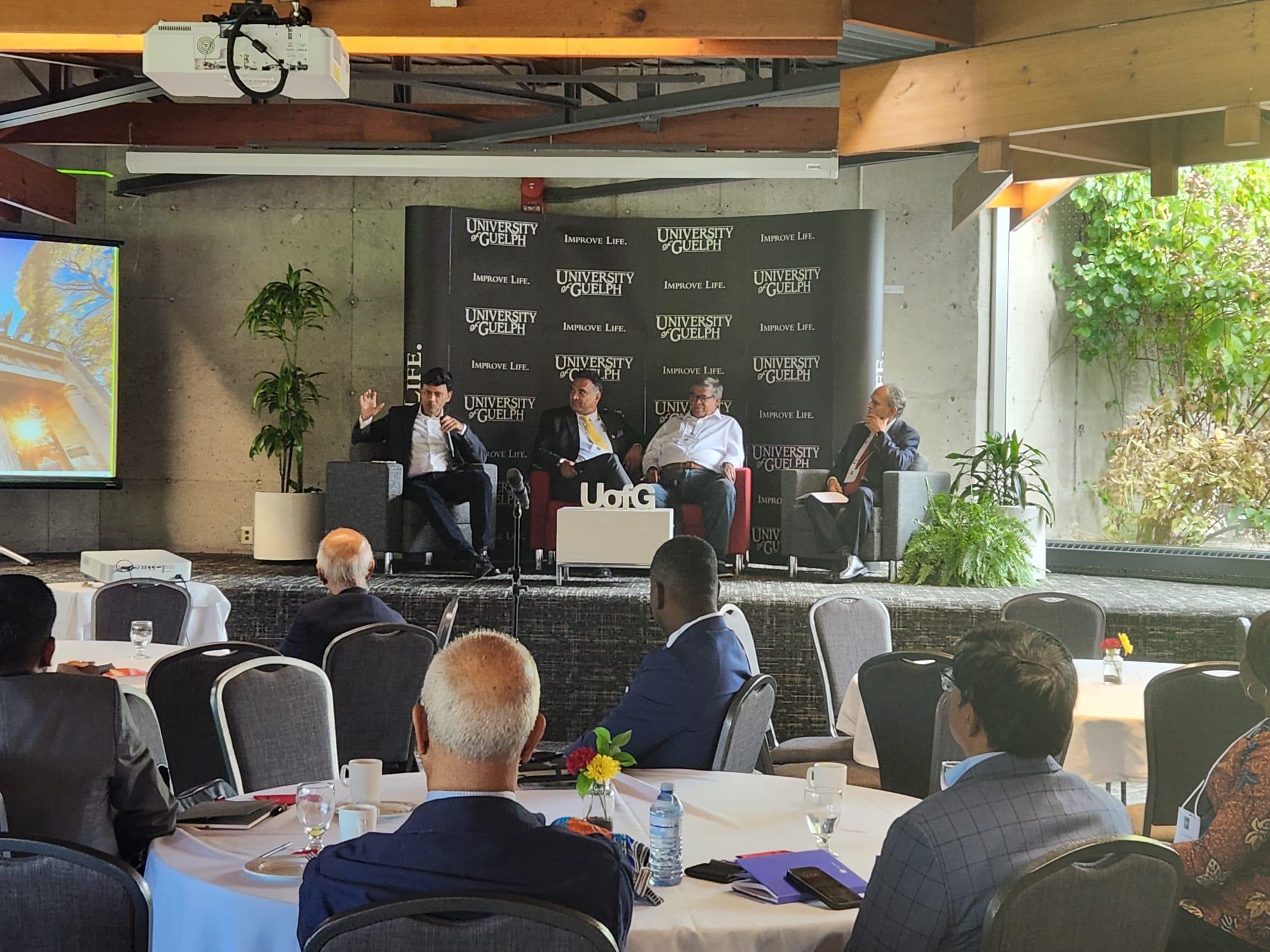 Four speakers sit on stage with audience looking on