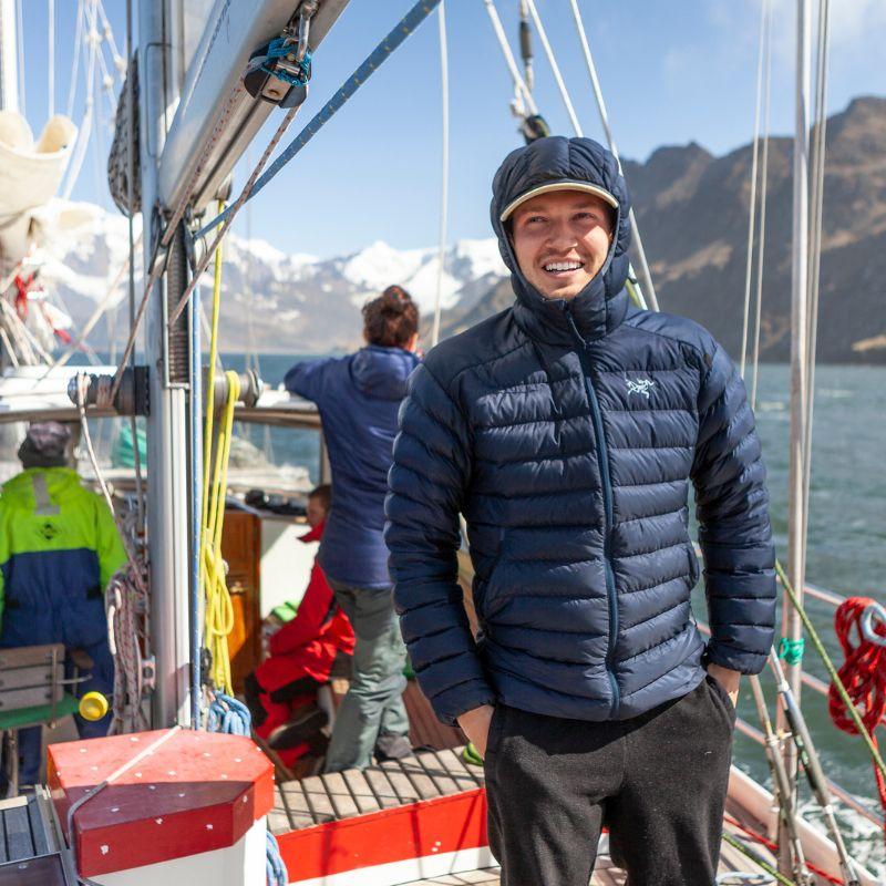 Man bundled up with a winter coat while riding a boat in the arctic