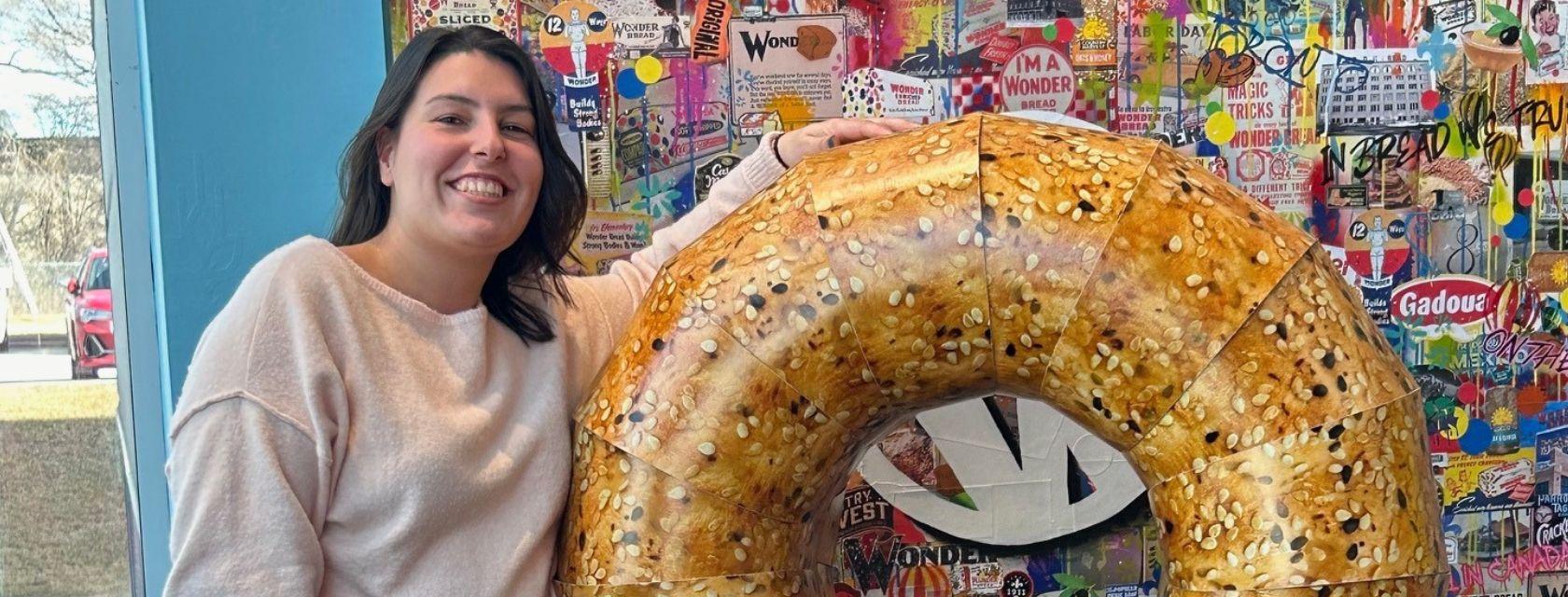 Guelph Grad standing with a giant bagel.