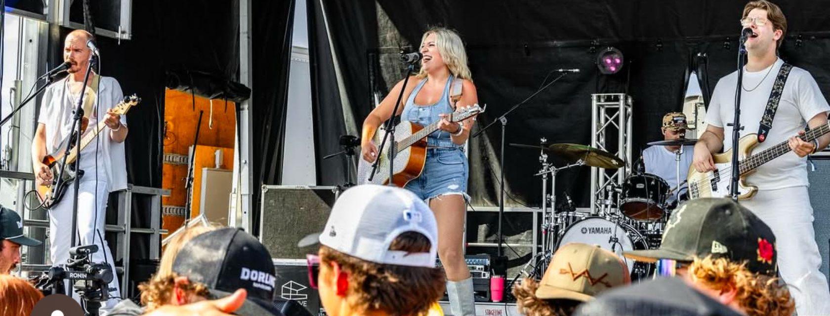 Paige Rutledge  playing a guitar while performing at a live music venue.