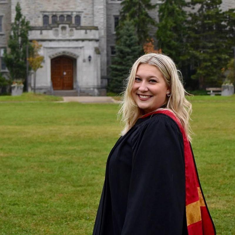 Paige Rutledge in her grad gown standing on Johnston Green.